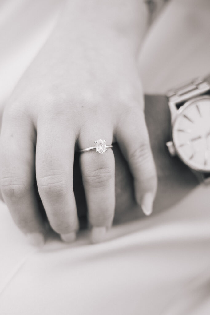 Couple holding hands with a close up of the ring
