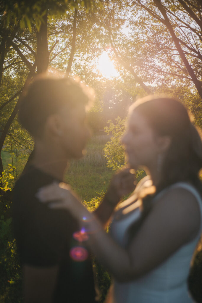 Couple standing in front a trees with sun behind and between them