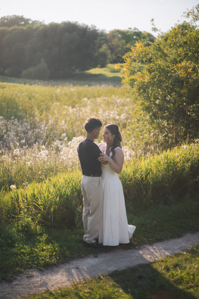 Couple standing infront of field of flowers with Sun behind them