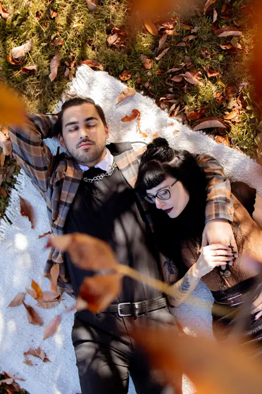 Couple resting peacefully in a bed of vibrant autumn leaves during a romantic portrait session in Ottawa