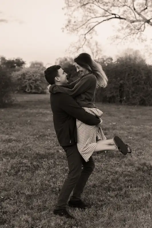 Man spinning his fiancée in the air during a joyful engagement portrait session at the Ottawa Arboretum.