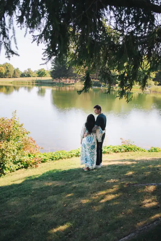 Couple standing together by the pond at Andrew Haydon Park in Ottawa, looking out over the water during a peaceful portrait session.