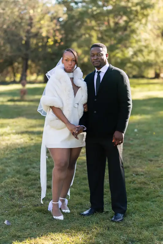Bride in a white gown and groom standing together in the Ottawa Arboretum during a vibrant autumn wedding portrait session