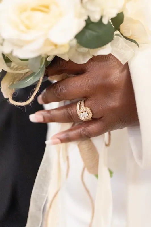 A very close-up, tight shot focusing on a bride's hands gently holding her vibrant, natural-style wedding bouquet.
