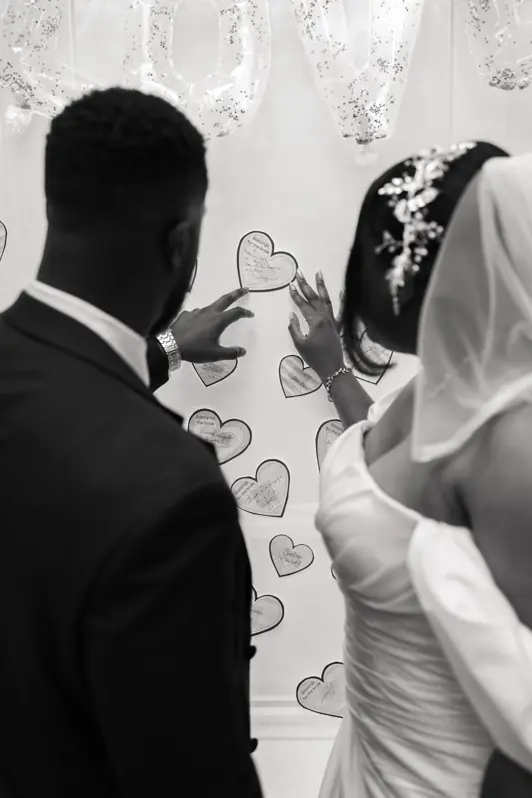 A bride and groom leaning in together, smiling as they read handwritten notes and well-wishes from their friends and family during their wedding reception.