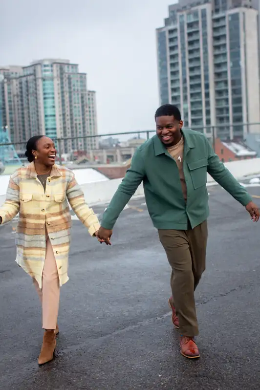 A couple walking hand-in-hand across the concrete rooftop of a parking garage in Ottawa's ByWard Market, with the city skyline in the background.