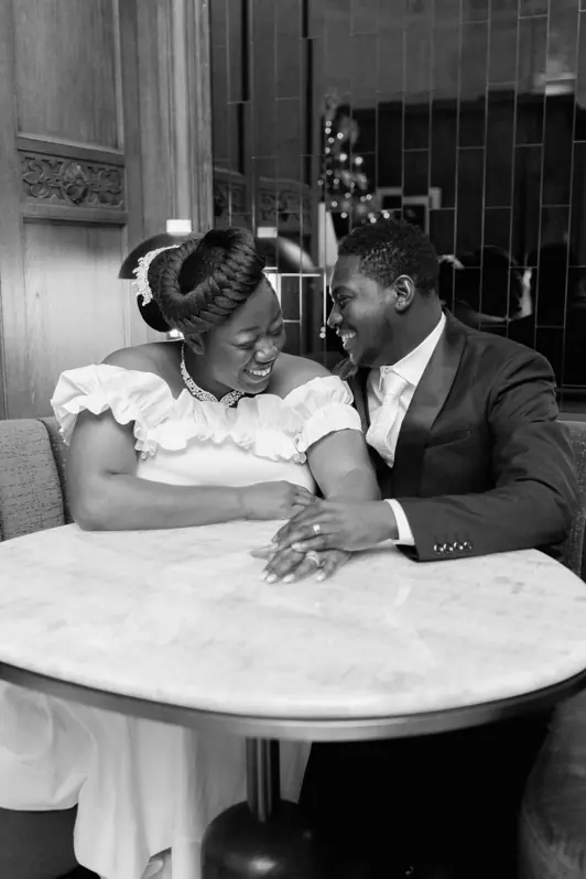 A bride and groom sitting at a beautifully set dinner table inside the Fairmont Château Laurier, sharing a genuine laugh during their wedding reception.