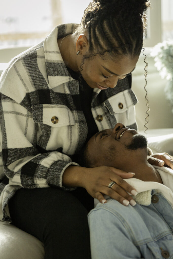 A close-up, intimate shot of a couple; the woman is looking down at her partner with a bright smile, and they are sharing a private, joyful moment.